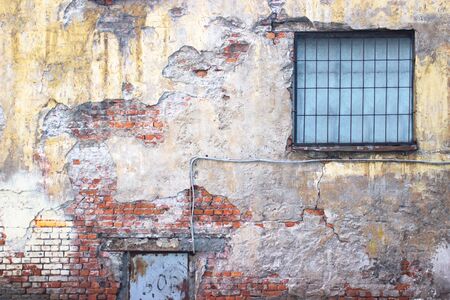 brick wall with damaged plaster, background shattered cement surfaceの写真素材
