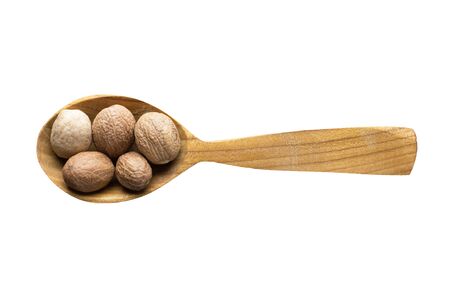 whole nutmeg for adding to food. spice in wooden spoon isolated on white. seasoning of delicious meal.の写真素材