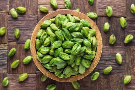 pistachios nuts peeled green in bowl on wooden table background.の写真素材