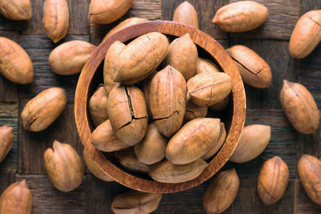 shelled pecan nuts fried with cocoa butter in bowl on wooden table background.の写真素材
