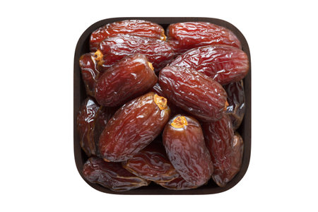 dried royal dates fruit in wooden bowl closeup. vegetarian food isolated on white.