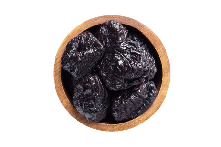 dried plums, prunes in wooden bowl isolated on white. healthy food top view.