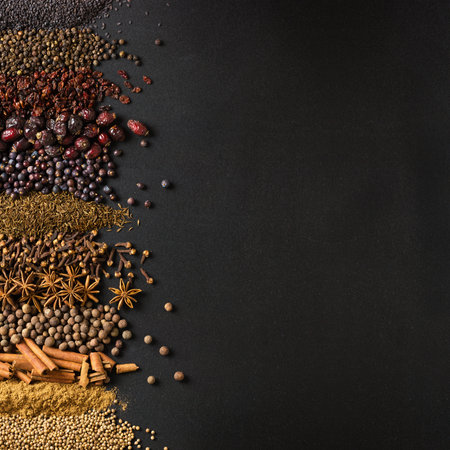 Large collection of spices and herbs on background of black table. Colorful conditions with empty...