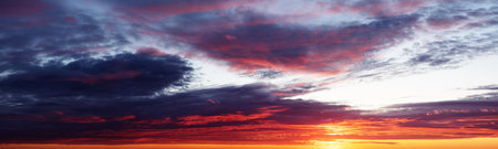 sunrise or sunset over the sea with brightly colorful clouds in the blue skyの写真素材