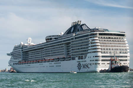 VENICE, ITALY - APRIL 13, 2013 : Criuse liner departing in Venice with tugboat assisting.のeditorial素材
