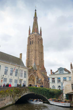 Bruges, Belgium - April 17, 2017: Tower of the church of Our Lady and traditional narrow street in the historical centre town of Bruges, Belgiumのeditorial素材