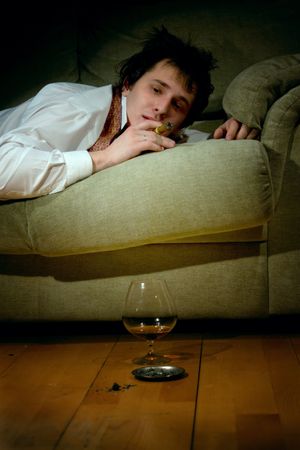 young man smoking cigar and drinking congac at nightの写真素材