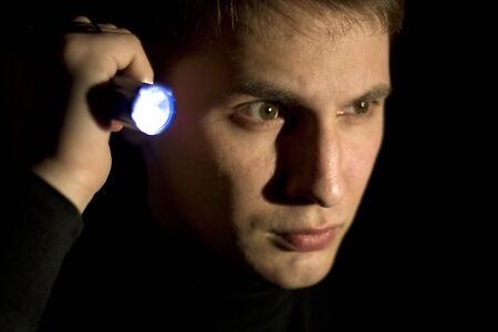 young man looking for something in the darkの写真素材