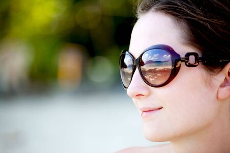 portrait of young woman in sunglasses with reflection of the sunny beachの写真素材