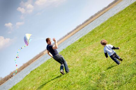 happy dad and son flying a kite togetherの写真素材