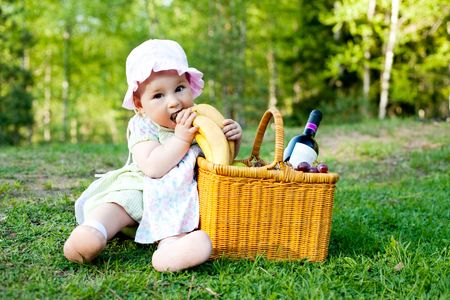 cute baby girl biting bananas lying in the basketの写真素材