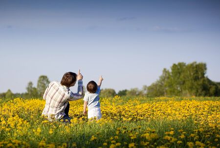 dad and little son pointing up in the field of dandelionsの写真素材