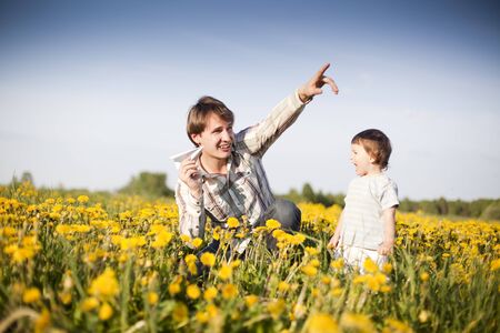 happy dad and son launch paper plane in the field of dandelionsの写真素材
