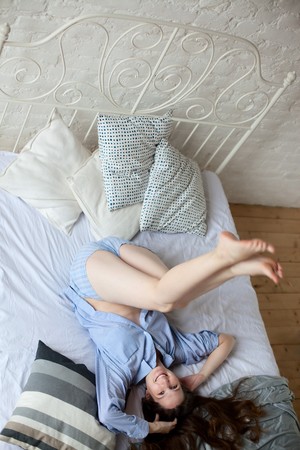 young woman having fun in a bedの写真素材