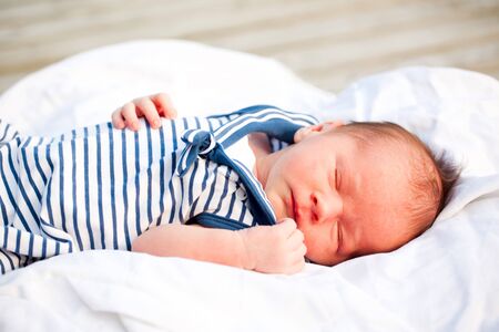 newborn boy sleeping peaceful outdoors in sailor jacketの写真素材