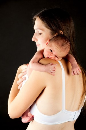 young happy mother holding his newborn boy over blackの写真素材