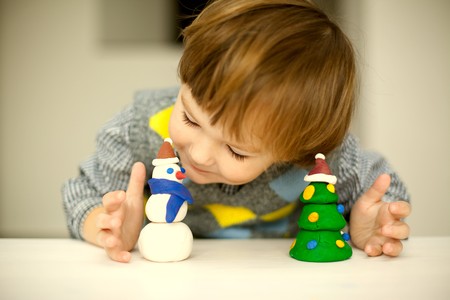 a child making a snowman and christmas tree of plasticineの写真素材