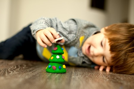 a child making a snowman and christmas tree of plasticineの写真素材