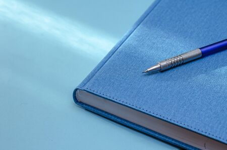 Closed blue notebook on a light turquoise background. Selective focus. Close-up. Calm color palette.の写真素材
