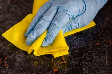 Close-up of a female hand cleaning a dark floor tile with a pattern. Professional housekeeping or home routine. Side view. Selective focus.の写真素材