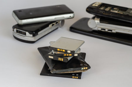 Group of used phones and batteries on a light background. Disposal and recycling. Eye level...