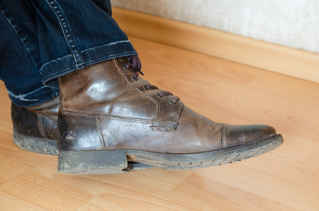 Dirty boots on a clean floor. Side view. Selective focus. Shooting inside the room.