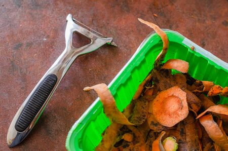 In a green plastic box strips of peel of raw carrots. The process of making homemade lunch. Close-up. Selective focus.の写真素材