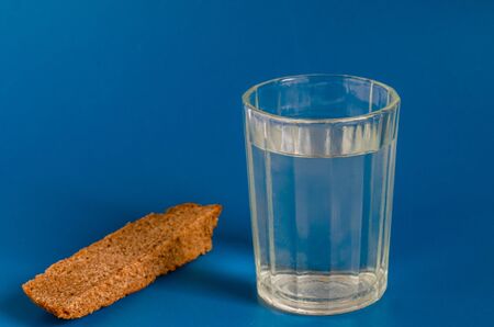 Faceted glass of strong alcohol and bread on a blue background. Close-up. Selective focus.の写真素材