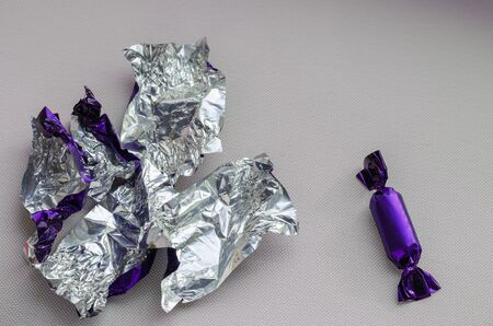 The only candy and a bunch of empty wrappers on a light background. View from above. Close-up. Selective focus.の写真素材