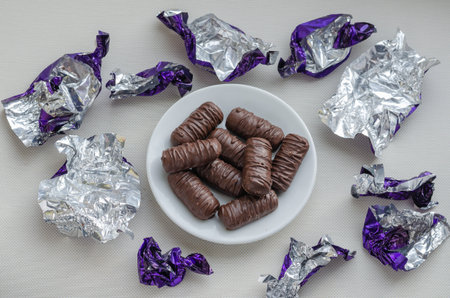 A small saucer with sweet treats on the table. Around the labels from eaten sweets. Sweet tooth or...