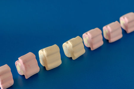 Mini marshmallows in on a blue background. Seven colorful marshmallows in a diagonal line. Selective...