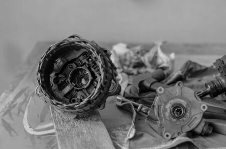 Details of a car generator on a workbench. Disassembled Used Automotive DC Generator. Repair used generator. Auto repair shop or service center. Selective focus. Black and white photo. Blurred background.の写真素材