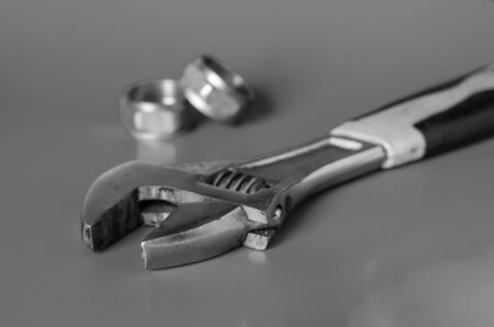 Adjustable Wrench and Two Nuts on a gray background. Concept plumber or home master. Selective focus. Eye level shooting. Close-up.の写真素材