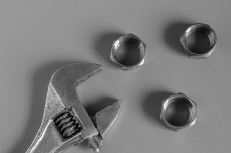 Adjustable wrench and three nuts on a grey background. Brass nuts for pipe compression fittings.  Close-up. Selective focus.の写真素材