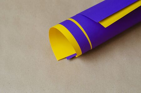 Close-Up Of Blue And Yellow Rolled Up Papers Against beige background. Two sheets of colored paper folded into a cylinder. Abstract background. Top view at an angle. Selective focus.の写真素材