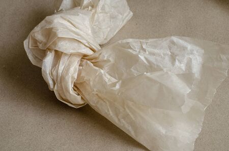 Wrapping paper tied in a knot. Crumpled piece of paper with a torn edge. Abstract background. Eye level shooting. Selective focus. Close-up.の写真素材