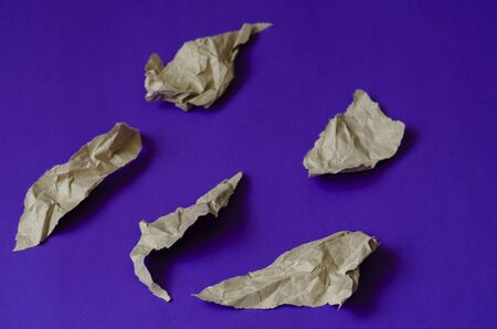 Blue background with pieces of brown paper. Five crumpled pieces of paper with torn edges. Abstract background. Top view at an angle. Selective focus. Close-up.の写真素材