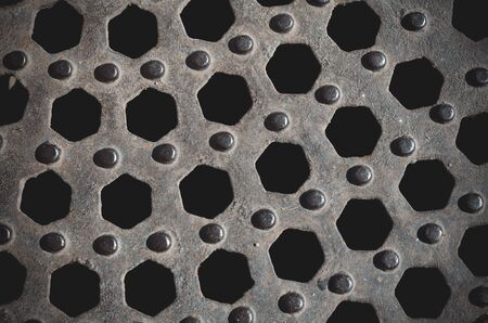 Abstract geometric background from hexagons. Repeated hexagonal holes and round protrusions in rusty metal. Multitask background for design tasks. Selective focus.の写真素材