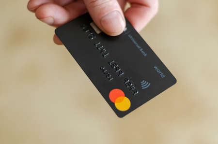 Ukraine, Odessa - April 04, 2020: a man holds out a bank card for payment. Contactless Bank Card Monobank. View from above. Selective focus. Close-upのeditorial素材