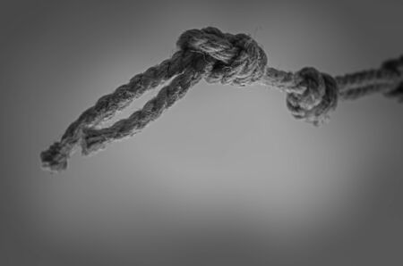Jute rope hanging from above with knots. Rope with rough knots in a receding perspective. The concept of striving up for a better or achieving a goal. Selective focus. Close-up. Shooting from the bottom up.の写真素材