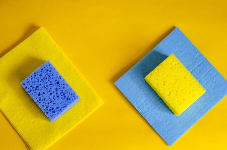 Kitchen sponges on yellow. Blue porous kitchen sponge and napkin for dishes. Hygiene and sanitation in the kitchen. Close-up. Selective focus.の写真素材