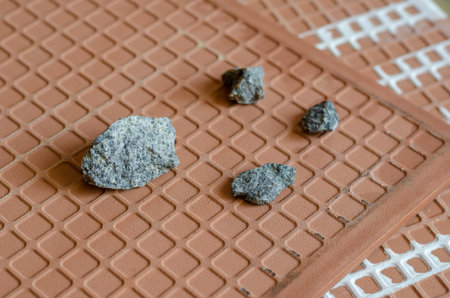 Ceramic tiles and crushed stone close-up. A detailed shot of four rubble stones on the back of a...