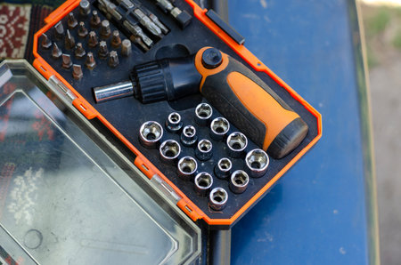 Screwdriver with a set of bits. Used bit set for screwdriver in plastic box. Hand tools in the...
