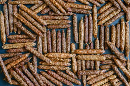 Dried pet sausages background. A lot of treats for dogs on a black table. Ornament of delicious dried carcasses for domestic dogs. Pet supplies. View from above. selective focus.の写真素材