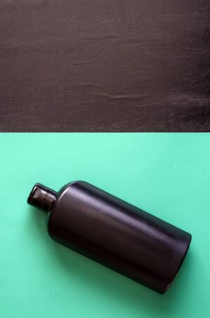 Black plastic bottle on a turquoise background. Black bottle of shampoo or shower gel. View from above. Free space for designer text.の写真素材