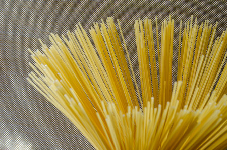 Spaghetti on a beige background. A bunch of spaghetti close-up. Group of dry spaghetti. Unprepared...