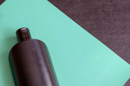 Black bottle of shampoo or lotion. Close-up of a plastic bottle on turquoise. Hygienic cosmetics. Copy space. Selective focus.の写真素材