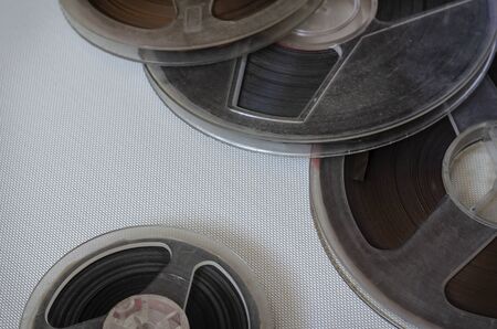 Reels with the tape on light background. Various bobbins with 60s audio recordings. Nostalgia, pleasant memories. Close-up. Selective focus.の写真素材