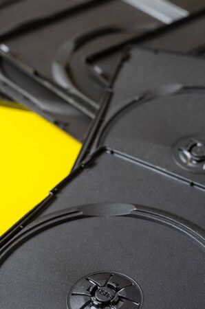 Group of empty DVD boxes on a yellow background. Black plastic boxes for compact discs. Creative multitask background. Focus in the foreground.の写真素材