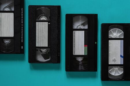 Old video cassettes with dust and scratches on a colored background. Four random turquoise videotapes. Creative background. Flat lay.の写真素材